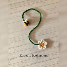 a beaded necklace with two flowers on it and the words educate beekeepers written below