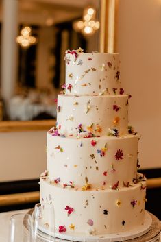 a three tiered white wedding cake with colorful confetti on the top and bottom