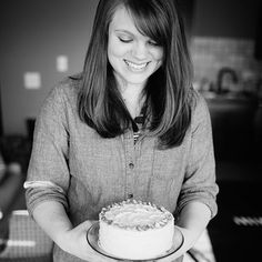 a woman holding a cake with white frosting