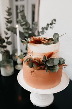 a three layer cake with greenery on top