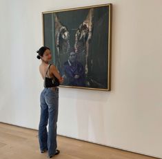 a woman is standing in front of a painting