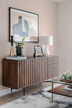 a living room with pink walls and a large painting on the wall above a wooden cabinet