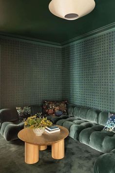 a living room filled with green velvet couches and a round coffee table in front of a window