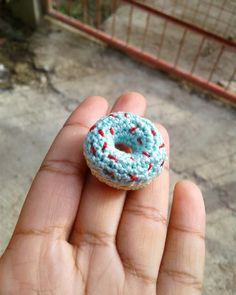 a small crocheted doughnut is held in someone's hand with red and blue sprinkles