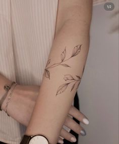 a woman's arm with a leaf tattoo on the left side of her arm