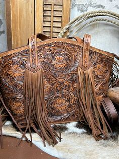 The Marfa Purse is a must-have for any fashion-forward individual. Crafted from tooled leather, this purse exudes luxury and sophistication. The leather fringe on the ends of the straps adds a touch of bohemian flair, making it perfect for any occasion. Make a statement with the Marfa Purse! Hand Tooled Western Bags, Western Brown Bag With Fringe, Brown Western Bag With Fringe, Western Leather Bag With Fringe, Traditional Fringe Bag, Turquoise Accessories, Tooled Leather Handbags, Rose Boutique, Purse Patterns