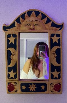 a woman taking a selfie in front of a mirror with the sun and moon on it