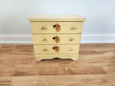 a yellow dresser with three drawers on top of it