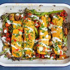 a white casserole dish filled with vegetables and meat covered in sauces on top