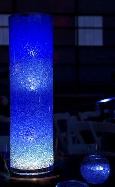 a tall blue vase sitting on top of a table next to two glass bowls filled with water