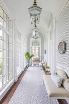 the hallway is decorated with white wicker walls and flooring, along with an ornate chandelier