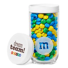 a jar filled with m and m candies next to a container full of m