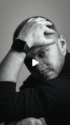 a man sitting at a table with his hands on his head and looking off to the side