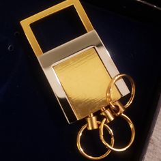 a pair of gold rings sitting on top of a black table next to a cell phone