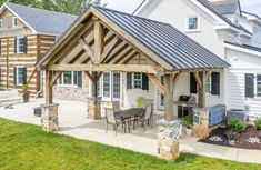 an outdoor kitchen and dining area in a home's back yard with stone pillars