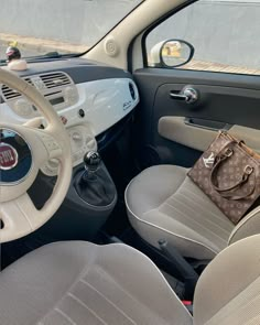 the interior of a small car with a purse on the dashboard