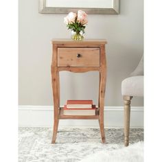 a small wooden table with two books on it and a chair in the corner next to it