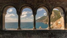 an arched stone wall overlooks the ocean and rocky coastline from a building with arches