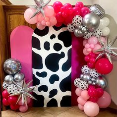 a skateboard decorated with pink, silver and white balloons in front of a mirror