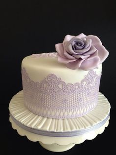 a white and purple cake with a flower on top