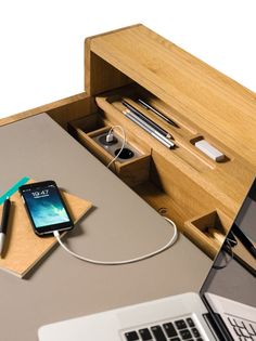 an open laptop computer sitting on top of a desk next to a phone and charger