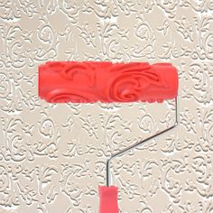 a pair of red paint rollers on top of a white wall with intricate designs