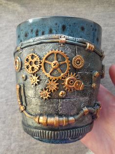 a hand holding a cup with gears on it