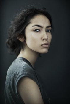 a woman is posing for a photo with her eyes closed and she has dark hair