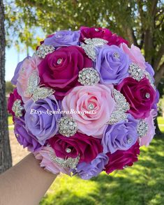 the bride's bouquet is made up of pink, purple and lavender roses with crystal brooches