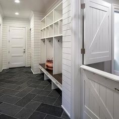 a hallway with white walls and black tile flooring