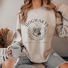 Our unisex wizard university sweatshirt are perfect for a cozy reading session or movie marathon! It's made of a soft cotton blend and features a vibrant direct to fabric transfer design that won't fade or crack. Show off your house pride in style and comfort. color pictured: sand Click this link if you aren't certain which house you are in: Official Hogwarts House Sorting Quiz | Wizarding World Care Instructions:• DO NOT dry clean• Machine wash COLD with mild detergent• Turn inside out when was Hogwarts House Sorting, Sweatshirt And Shirt Outfit, Hogwarts Sweatshirt, Hery Potter, Hogwarts Shirt, Classe Harry Potter, Hogwarts Outfits, Sweatshirt Ideas, Harry Potter Items