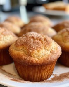 several muffins on a white plate with powdered sugar sprinkled on top