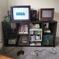 there are two televisions on top of the shelf with video game consoles in front of them