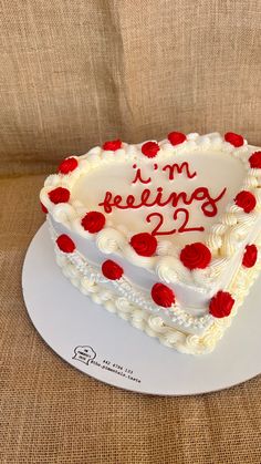 a heart shaped cake with the words i'm feeling 21 on it sitting on a plate