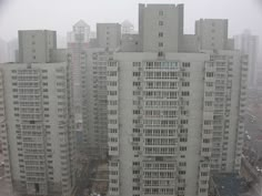 an aerial view of some tall buildings in the city on a foggy, overcast day