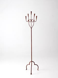 a metal coat rack with three candles on it's sides and one candle holder in the middle