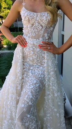 a woman in a wedding dress posing for the camera with her hands on her hips