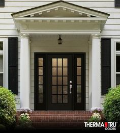 a white house with black front doors and two sidelights on either side of the door