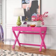 a pink desk with two drawers and a lamp on it in front of a white wall