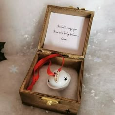 an open wooden box with a christmas ornament in it and a red ribbon