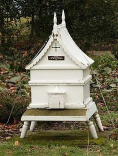 a white bird house sitting on top of a lush green field