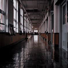 a long hallway with lots of windows and tiled flooring on both sides of it