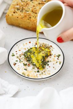 someone is pouring olive oil on a plate with bread