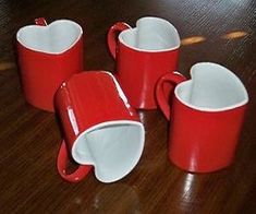 four red and white coffee mugs sitting on top of a wooden table