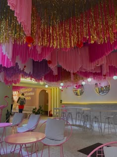 pink and gold streamers hang from the ceiling in a room filled with tables and chairs