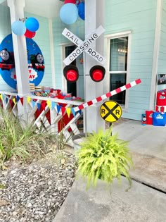 there is a train crossing sign in front of a house with balloons and streamers