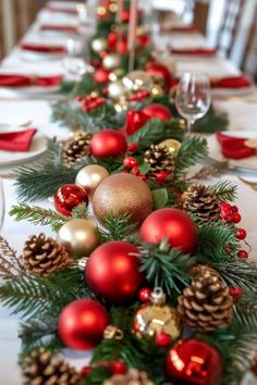 the table is set with red and gold ornaments, pine cones, candlesticks and evergreen branches