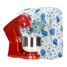 a red mixer sitting next to a blue flowered napkin on top of a table