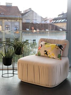 a white chair sitting next to a window with a plant on it's side