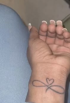 a woman's wrist tattoo with a heart and cross in the middle on her left hand